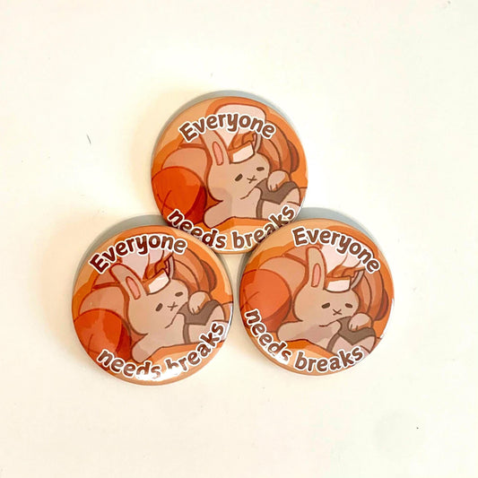 A picture of three buttons with a tired bunny drawing on it with words that say “Everyone needs Breaks”